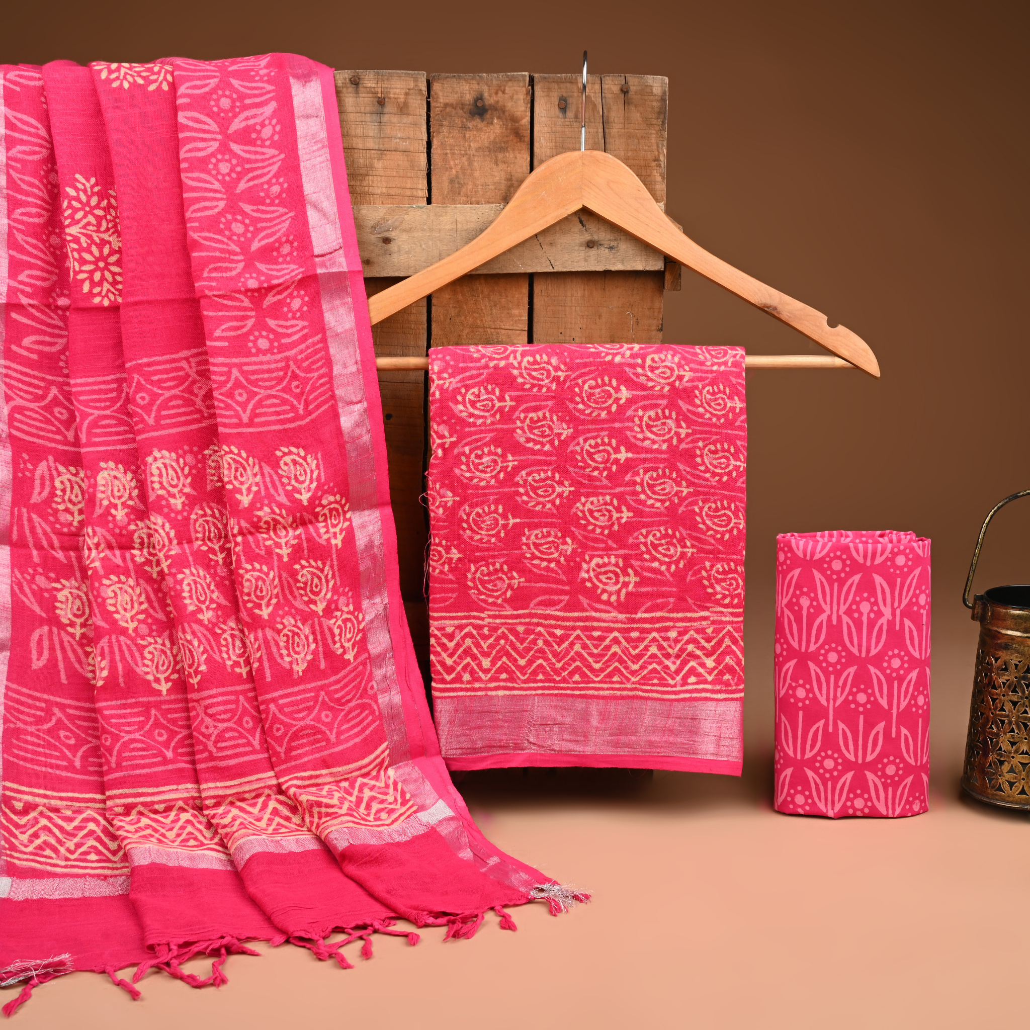Pink fabric with white patterns on a wooden hanger against a brown background