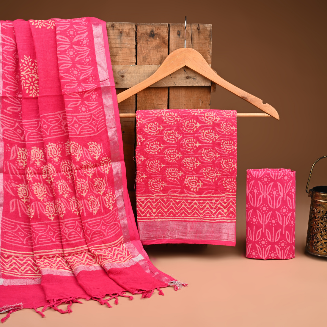 Pink fabric with white patterns on a wooden hanger against a brown background