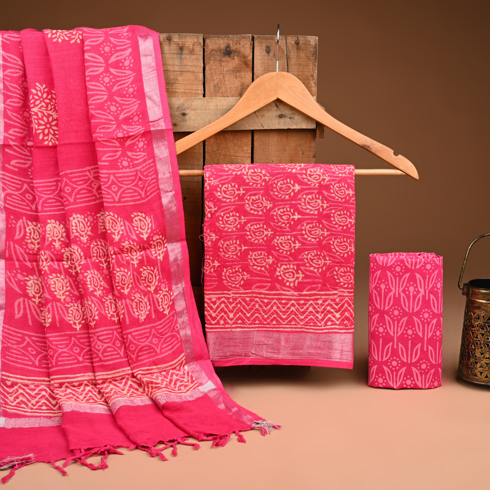 Pink fabric with white patterns on a wooden hanger against a brown background