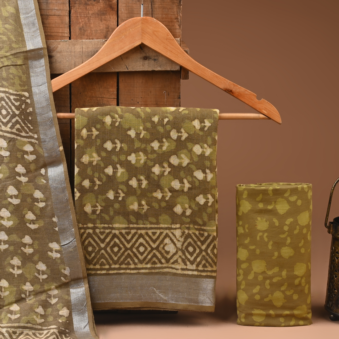 Green patterned fabric draped over a wooden hanger against a brown background