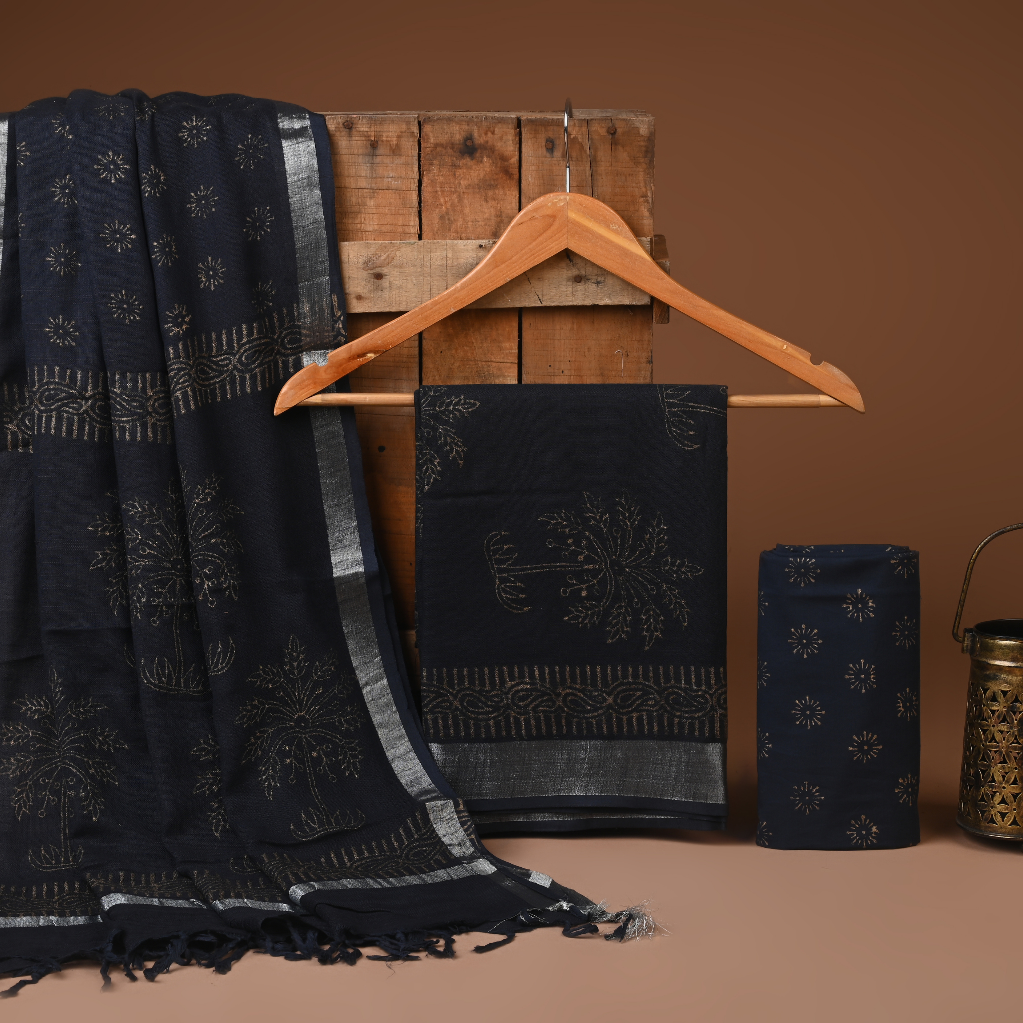 Black embroidered fabric on a wooden hanger against a brown background