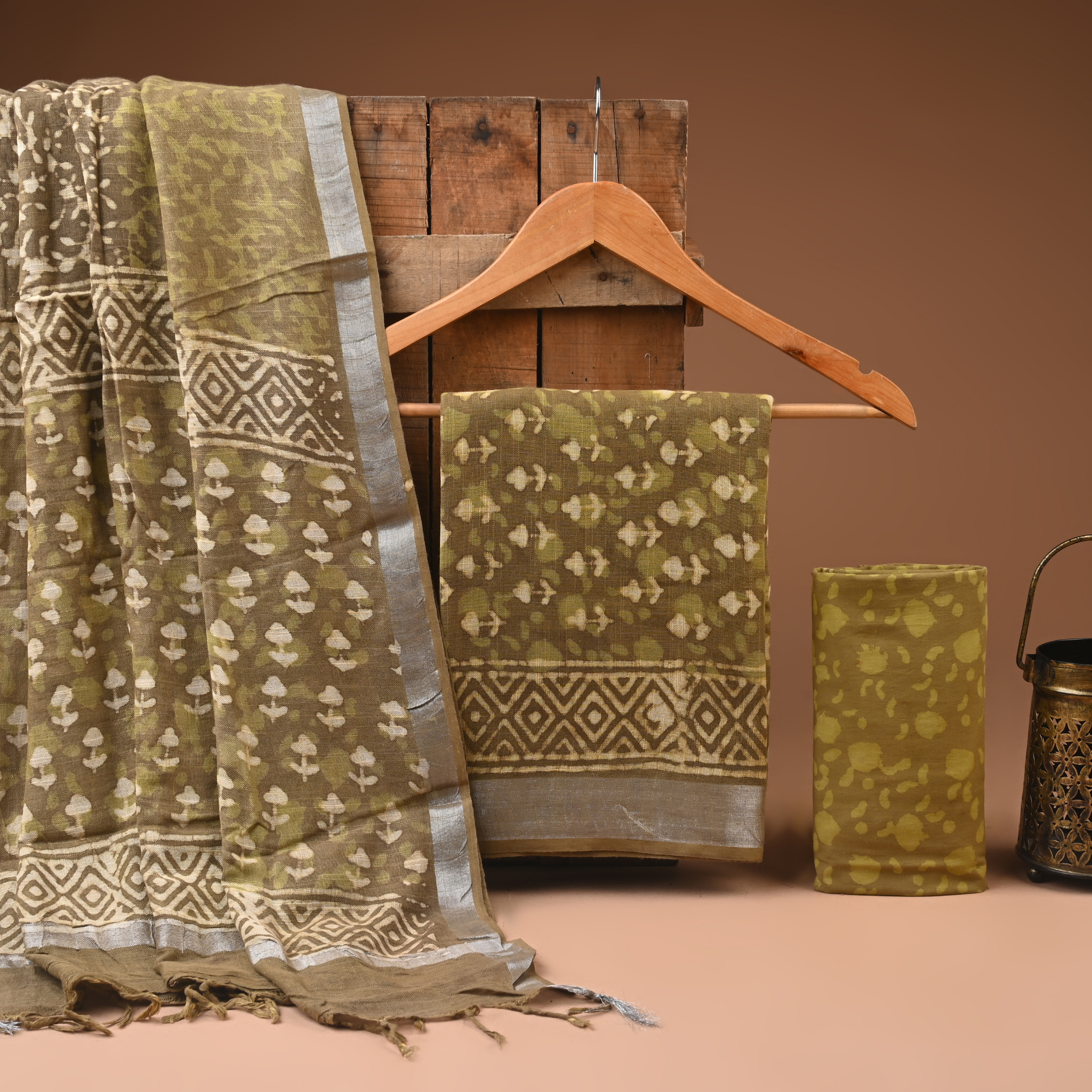 Green patterned fabric draped over a wooden hanger against a brown background