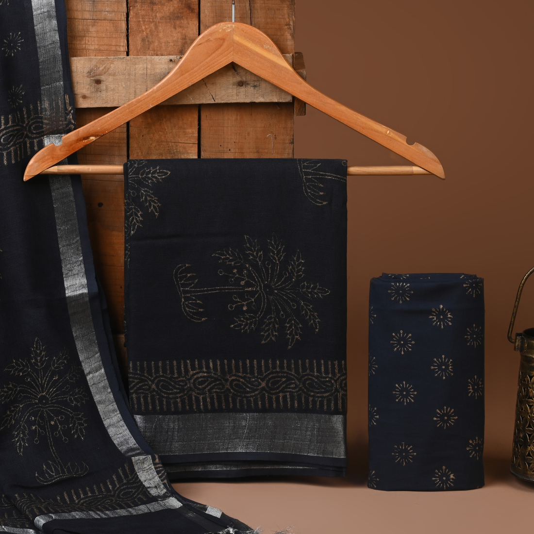 Black embroidered fabric on a wooden hanger against a brown background